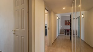 Un pasillo con piso de madera, paredes blancas y una puerta con picaporte de latón.
