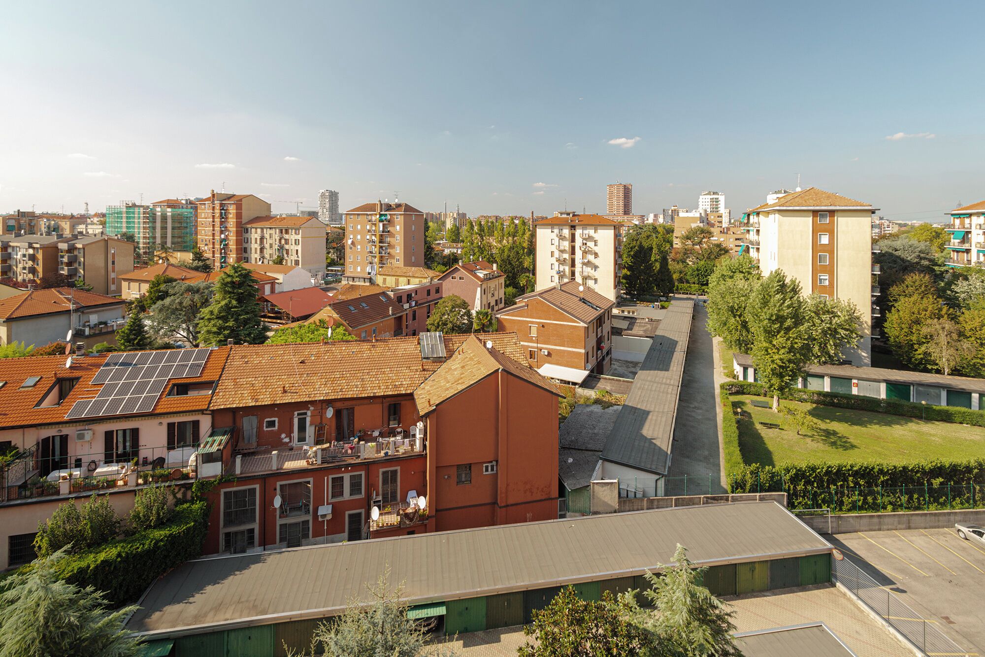 A residential area with various buildings, including a large red building with solar panels on the roof.