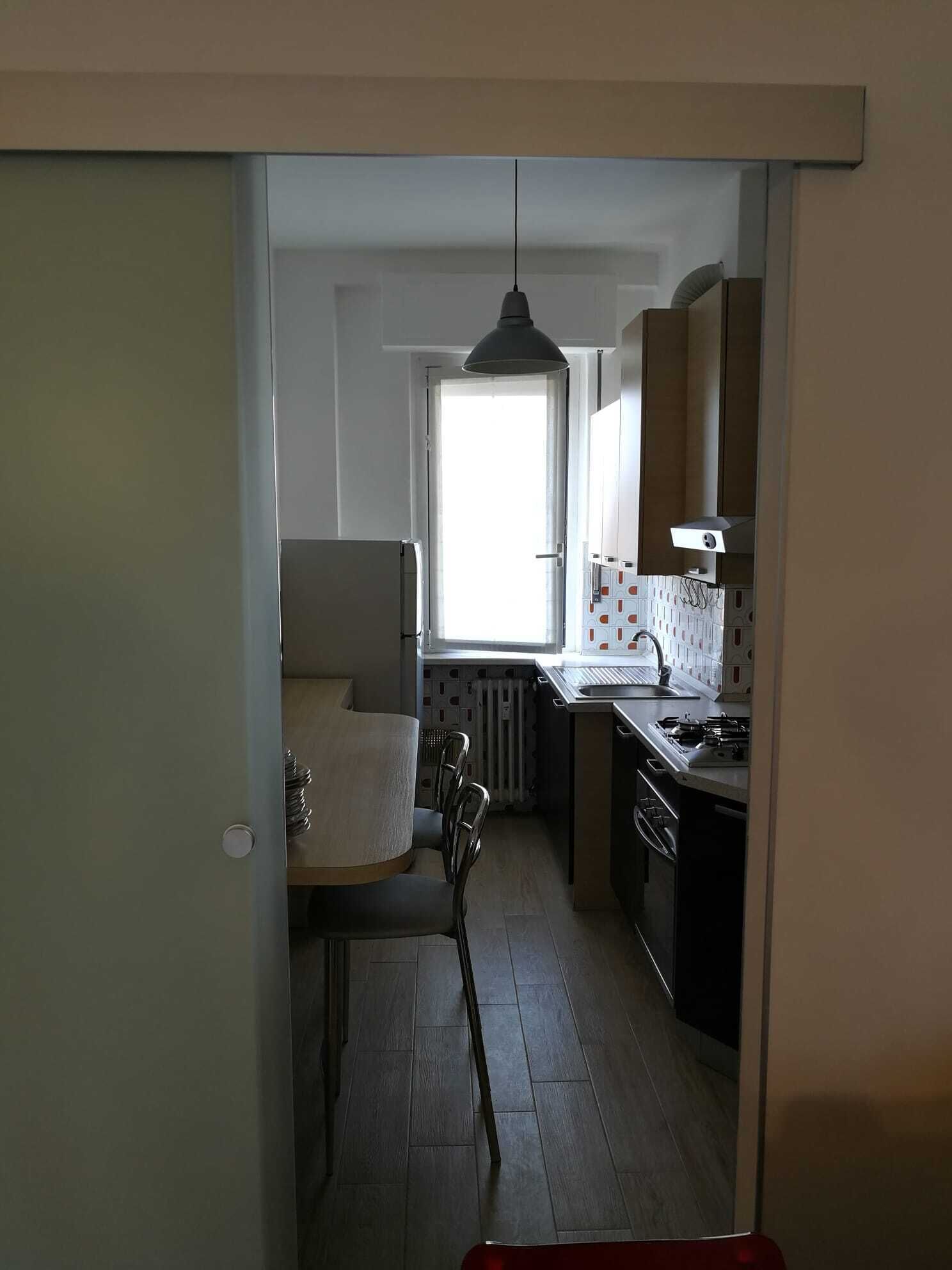 A compact kitchen with a dining area, a window providing natural light, and a radiator under the window.