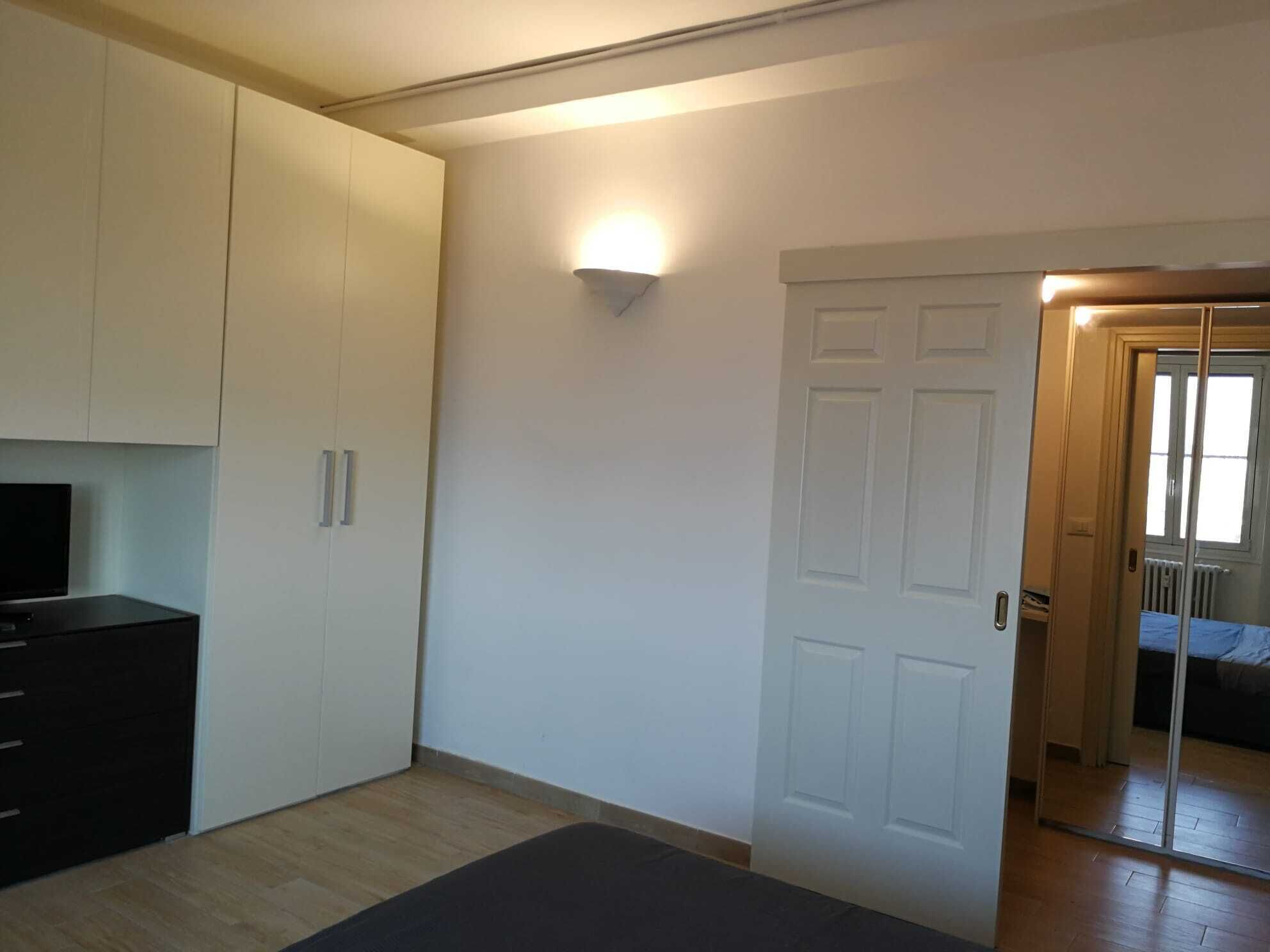A bedroom with a bed, a wardrobe, and a television.