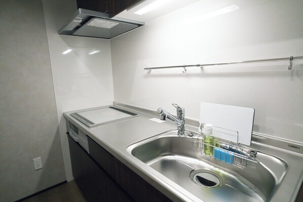 Una cocina moderna con electrodomésticos de acero inoxidable, un lavamanos con dispensador de jabón y un perchero para toallas.