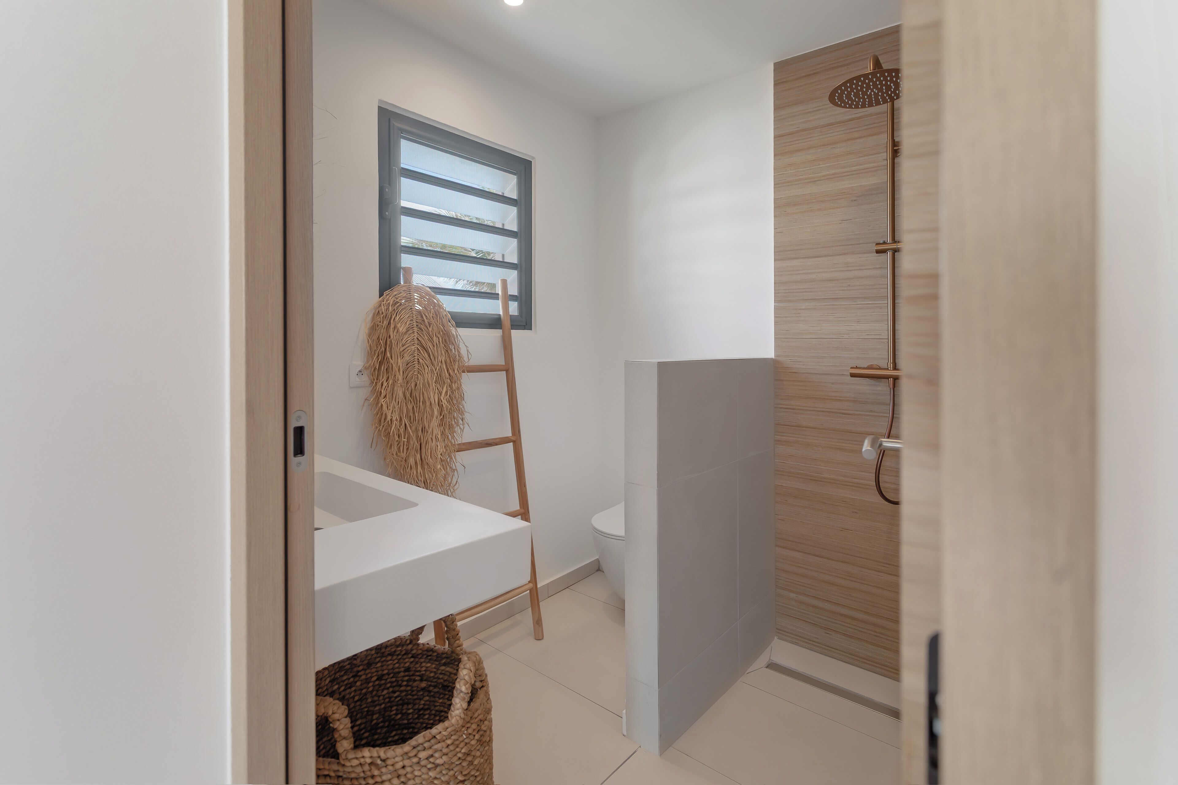 A modern bathroom with a wooden shower, a white sink, and a wooden ladder.
