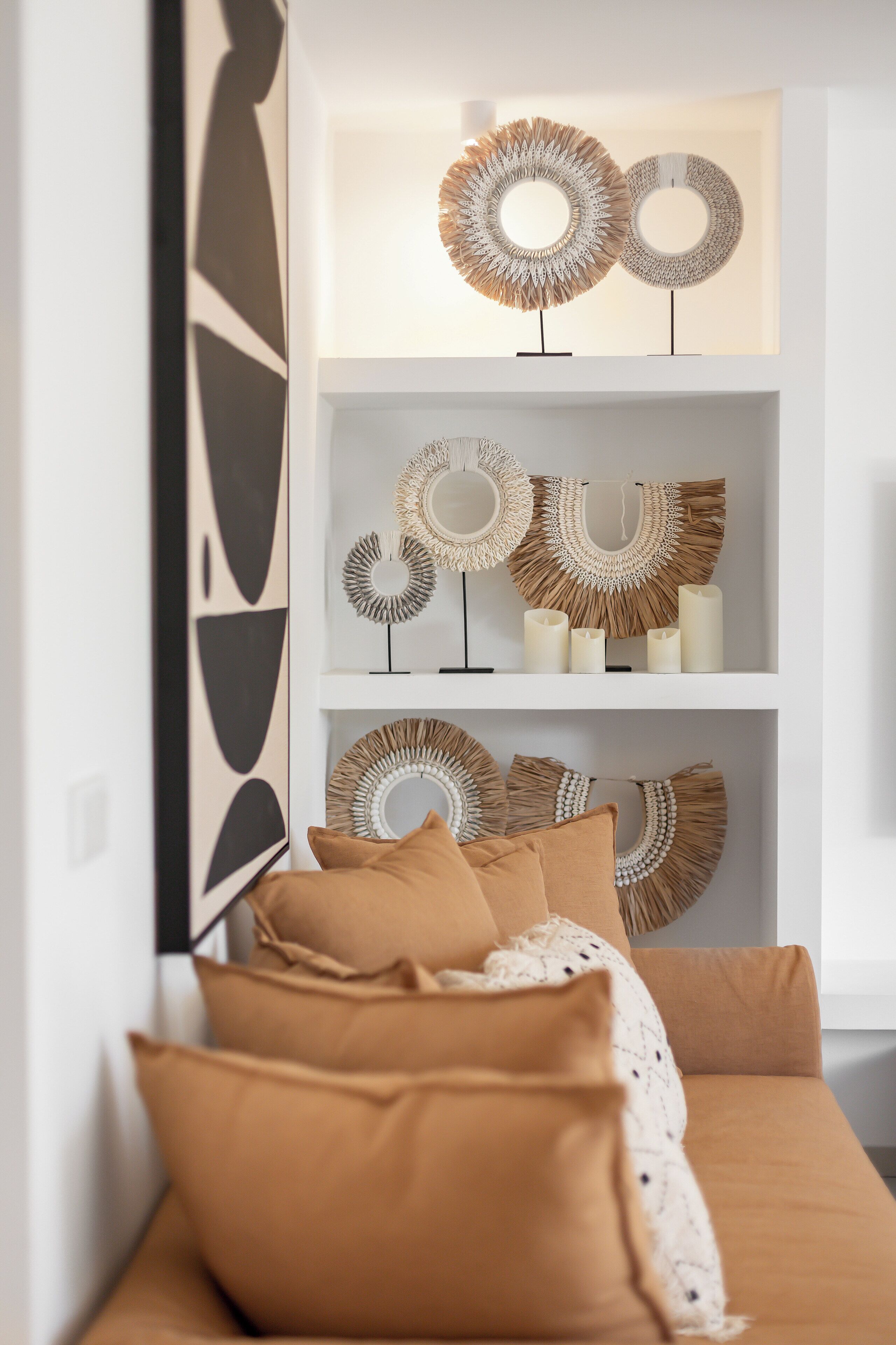 A modern living room with a sofa, decorative wall art, and a white shelf with various items.