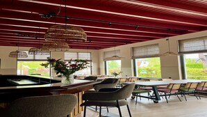 A restaurant with a red ceiling, large windows, and wicker pendant lights. - Group accommodation for 40 guests (Scherpenzeel (FR))