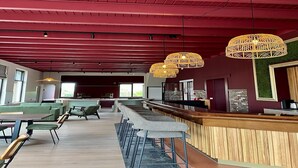 A modern bar area with a red ceiling, wooden bar counter, and multiple seating options including bar stools and tables. - Luxury Group Retreat in Nature (Scherpenzeel (FR))