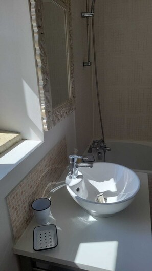 Un baño con lavamanos blanco, espejo y ducha.