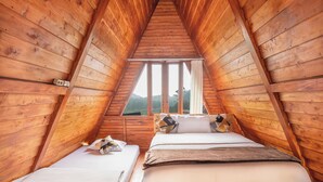 A wooden attic bedroom with two beds, a window, and a view of the outdoors. - Diamond Cabin House (Dieng Kulon)