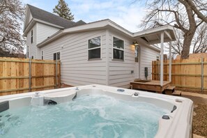 Een huis met een jacuzzi in de achtertuin, omringd door een houten schutting.
