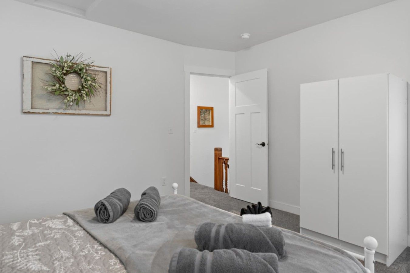 A bedroom with a bed, a wardrobe, and a door leading to another room.