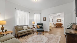 Un salon comprenant un canapé, un fauteuil et un coin repas avec des chaises et une table.