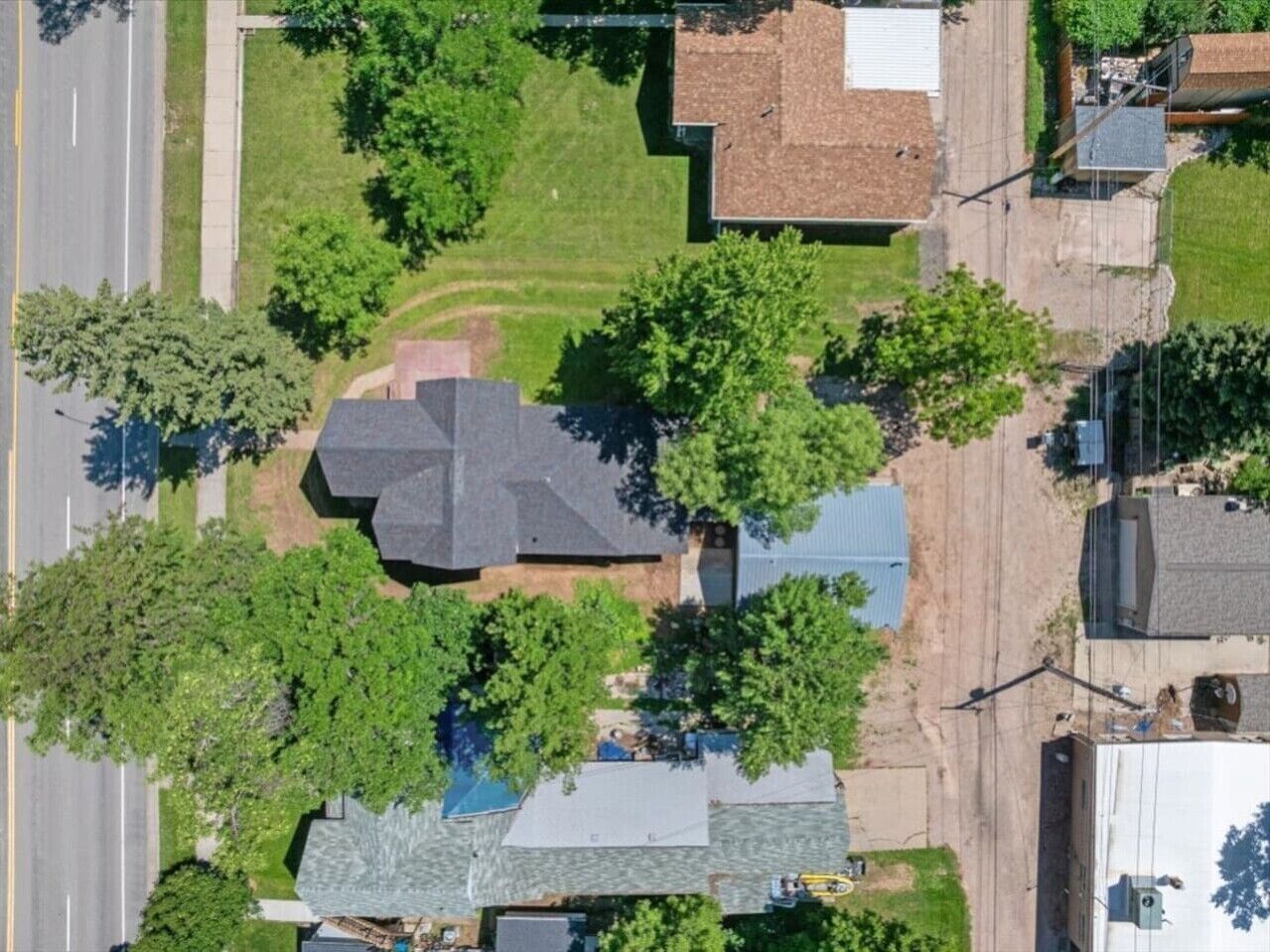 An aerial view of a residential area with houses, a road, and greenery.