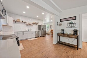 Een moderne keuken met witte kasten, houten vloeren en een koffiehoek.