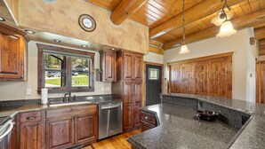 A kitchen with wooden cabinets, granite countertops, and a stainless steel dishwasher. - Golf Course, Sleeps 12, Garage (Sturgis)