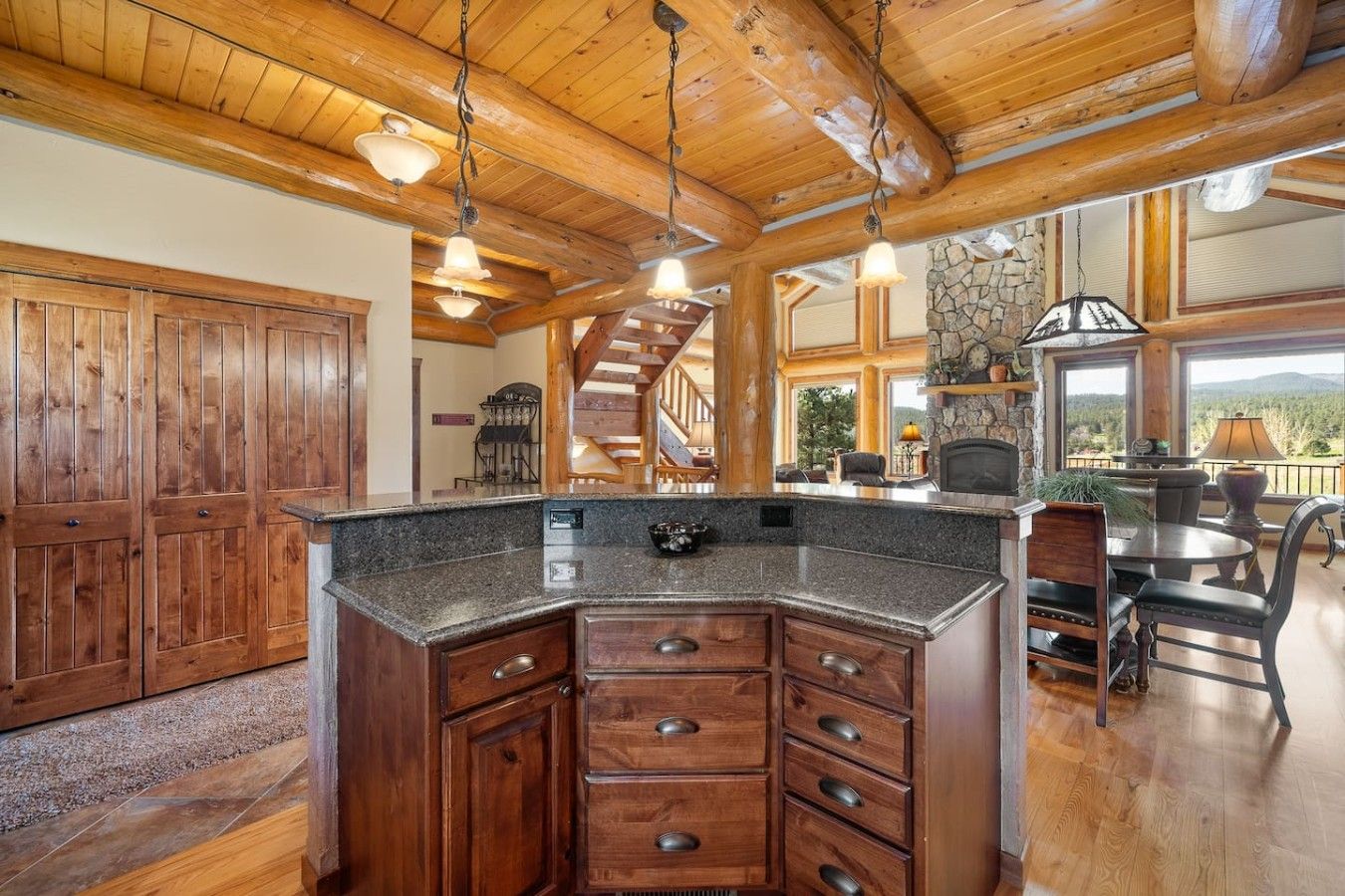 A spacious kitchen with a granite countertop, wooden cabinets, and a stone fireplace.
