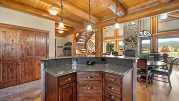 A spacious kitchen with a granite countertop, wooden cabinets, and a stone fireplace.