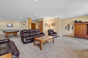 A living room with a pool table, leather sofas, a wooden coffee table, and a cabinet. - Golf Course, Sleeps 12, Garage (Sturgis)