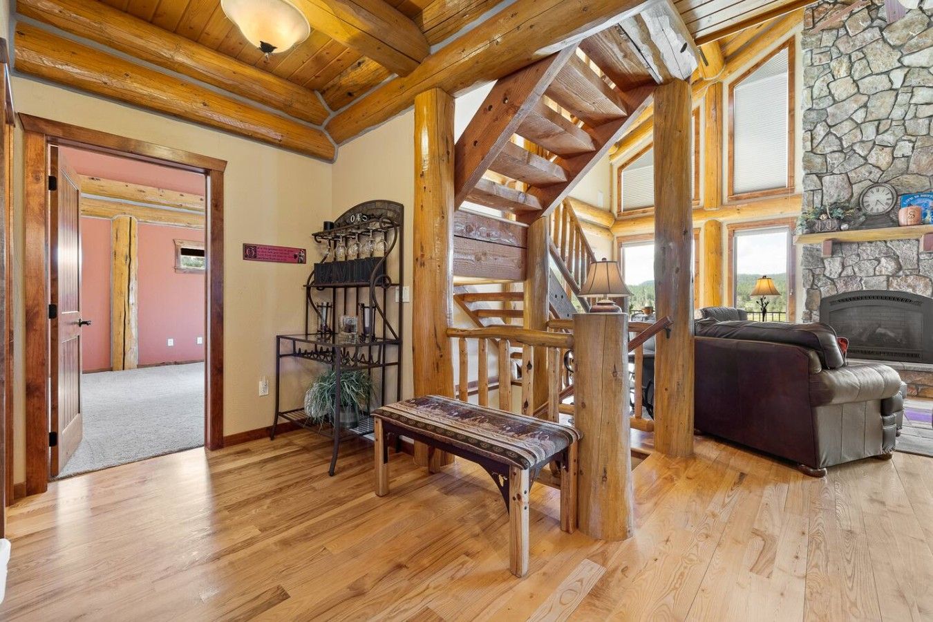 A wooden interior with a staircase, a fireplace, and a seating area.