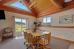Een eetruimte met een houten tafel en stoelen, een open haard en uitzicht op de omgeving.