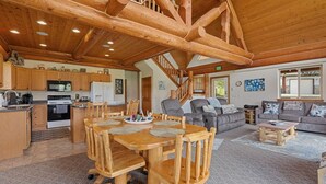 Una cocina amplia con armarios de madera, un comedor con mesa y sillas de madera, una sala de estar con sofá y mesa de centro, y una escalera que conduce a un nivel superior.