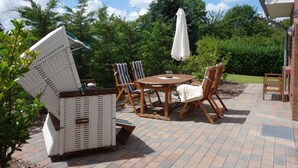 An outdoor patio with a round table, chairs, and a white wicker sofa.