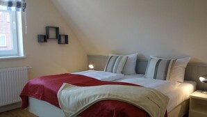 A bedroom with a bed, bedside tables, a window, and a radiator.