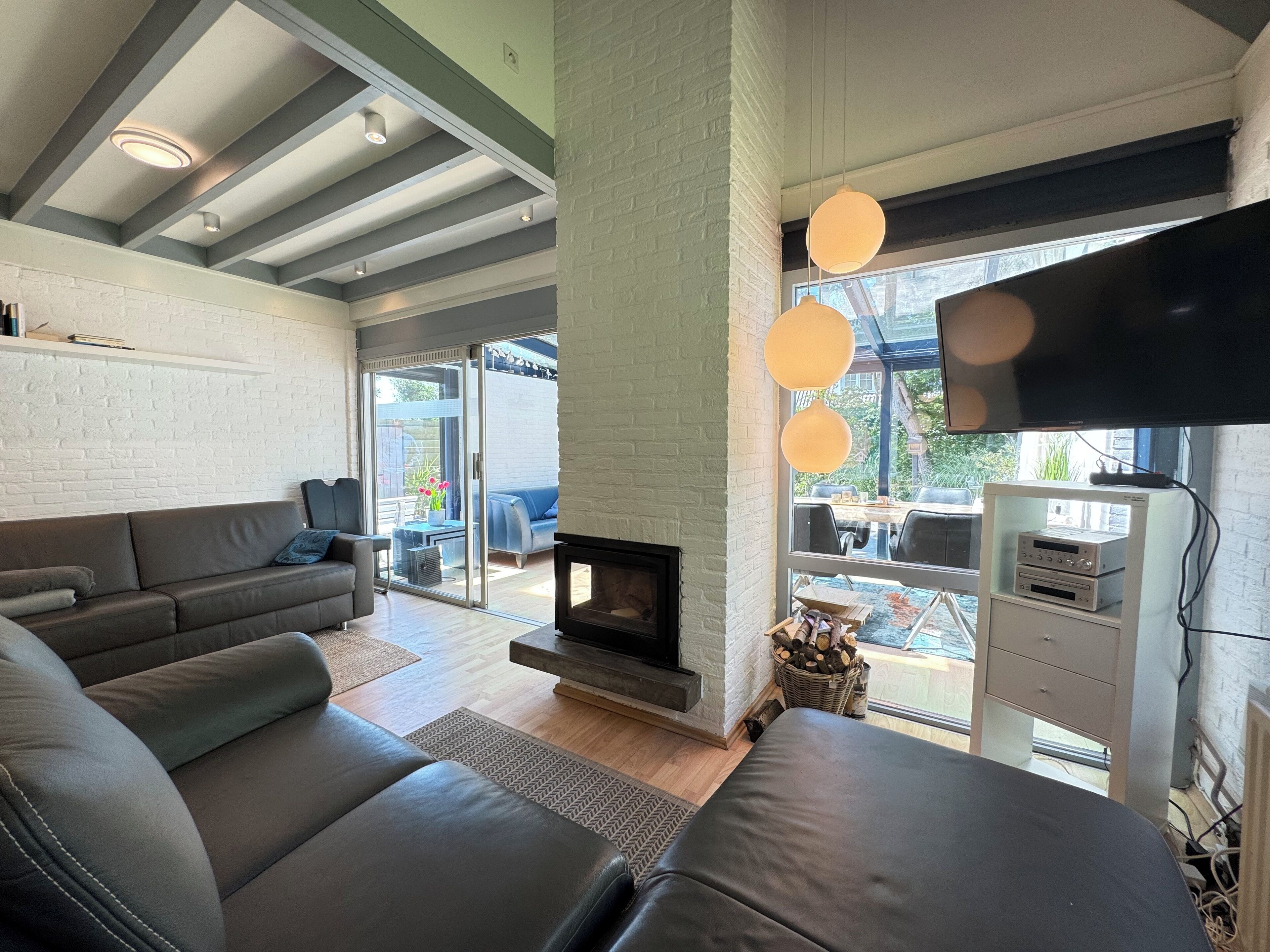 A modern living room with a fireplace, leather sofas, and a television.