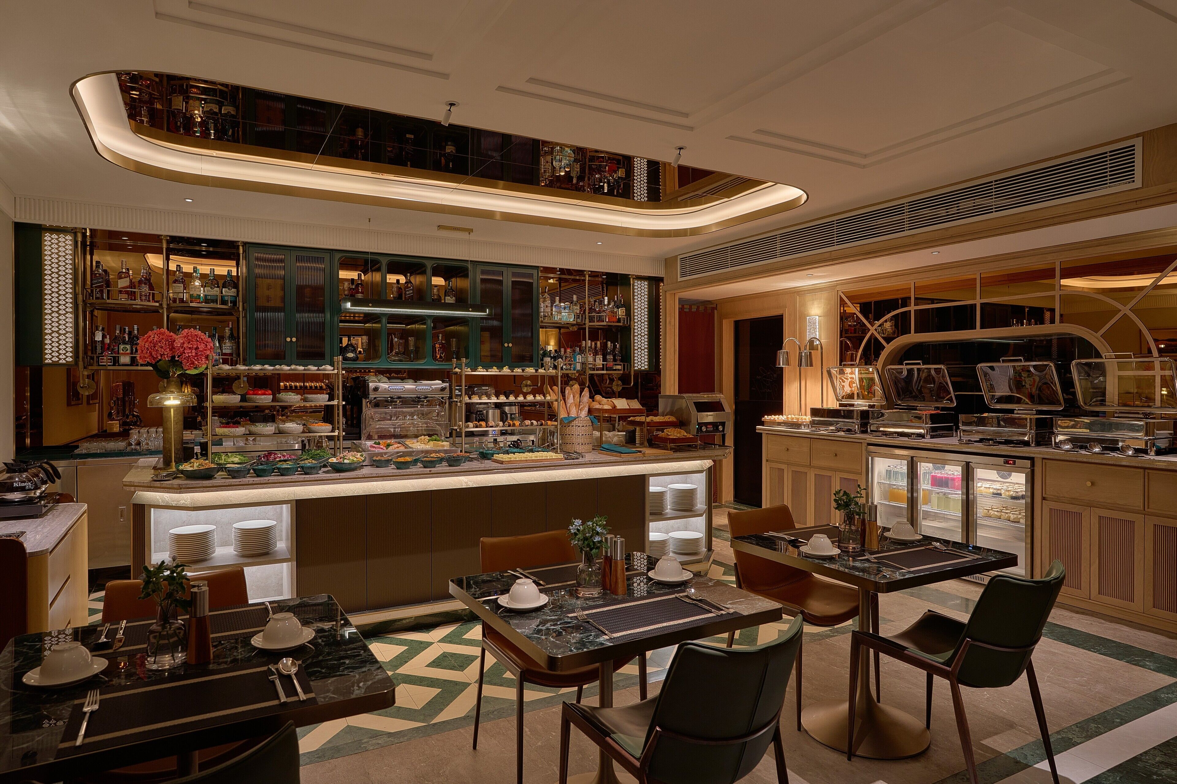 Un hall d’hôtel moderne doté d’un bar central, de différents espaces aménagés pour s’asseoir et d  ’un plafond décoratif.