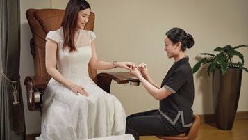 A woman in a white dress receiving a manicure.