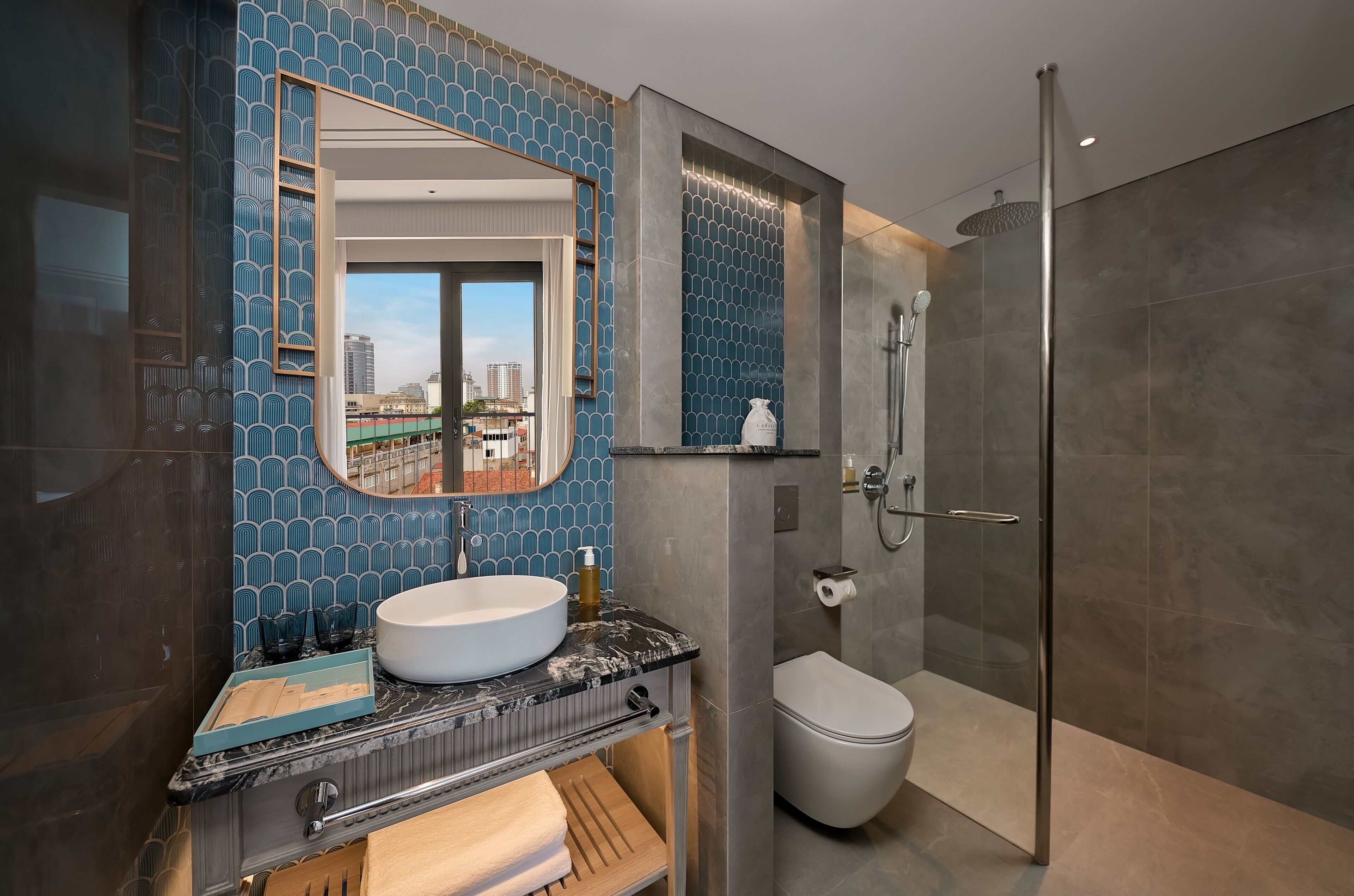 A modern bathroom with a large mirror, a round sink, a toilet, and a shower.