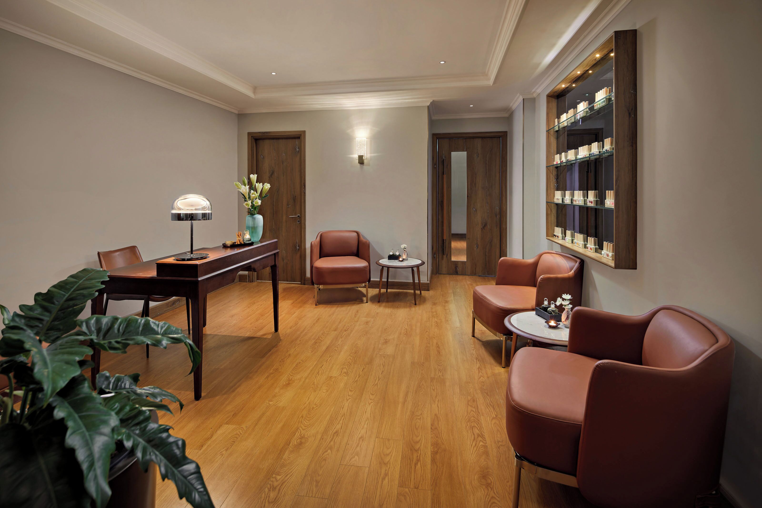 Una habitación de hotel moderna con suelo de madera, asientos de cuero, un área de comedor y una estantería.