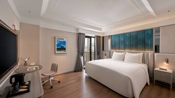 Een moderne hotelkamer met een groot bed, een bureau met koffiezetapparaat, een stoel en een televisie.
