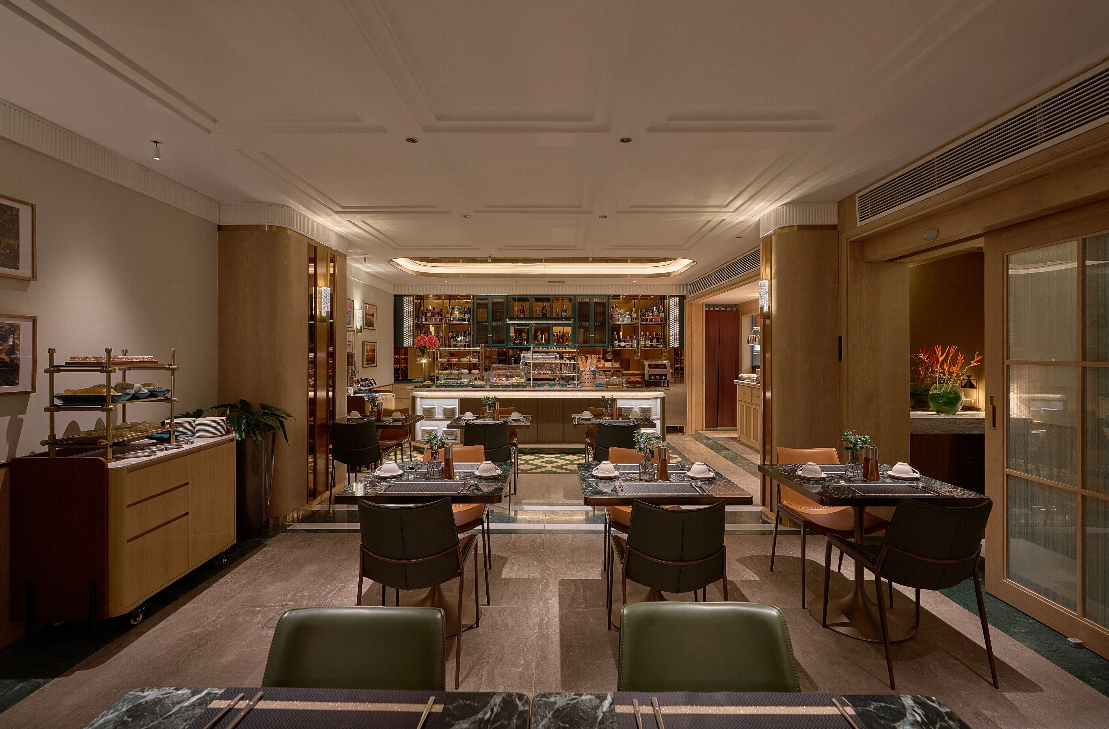 Un hall d’hôtel doté d’un bar central, de plusieurs espaces aménagés pour s’asseoir et d’un comptoir de réception.