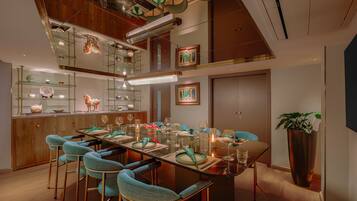 Un espace repas moderne avec une table en verre, des chaises de couleur turquoise et un plafond en bois.