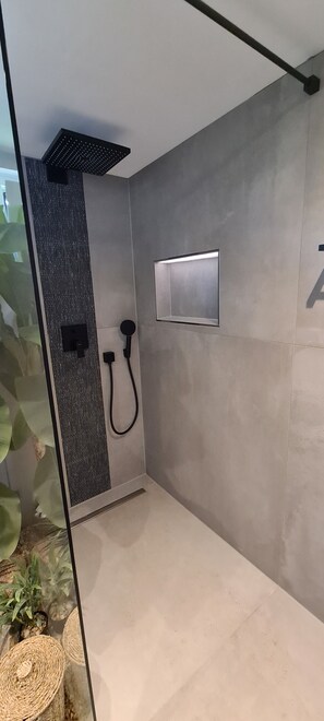 A modern shower with a glass enclosure, a control panel, and a textured wall. - Modern vacation bungalow in the Neuhof forest settlement on the Großer Wünsdorfer See lake (Zossen (Neuhof))