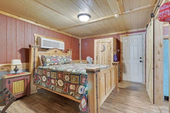 Camera da letto in legno con un letto, un comodino, una lampada e una porta con decoro a mezzaluna.
