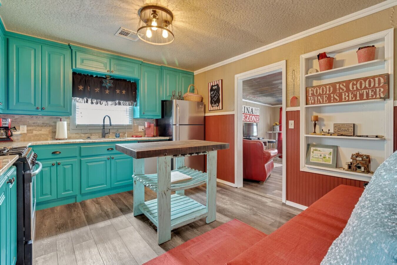 A kitchen with teal cabinets, a wooden table, and a red sofa.