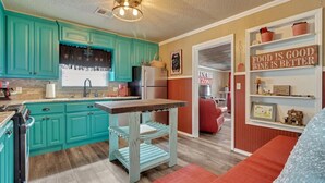 Una cocina con armarios azul turquesa, una mesa de madera y un sofá rojo.