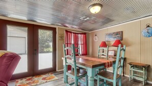 Una habitación acogedora con una mesa de comedor de madera, sillas azul verdosas, una lámpara roja y un reloj en la pared.