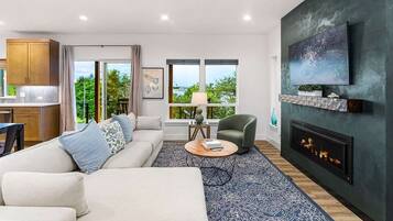 A modern living room with a sofa, a coffee table, a fireplace, and a TV mounted on the wall.