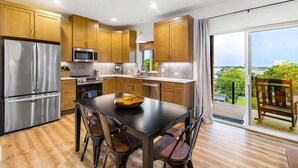 Une cuisine moderne dotée de meubles en bois, d’appareils électroménagers en acier inoxydable et d’un coin repas offrant une vue sur l’extérieur.