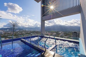 Una piscina a sfioro sul tetto con vista sulla città, tra cui montagne ed edifici.