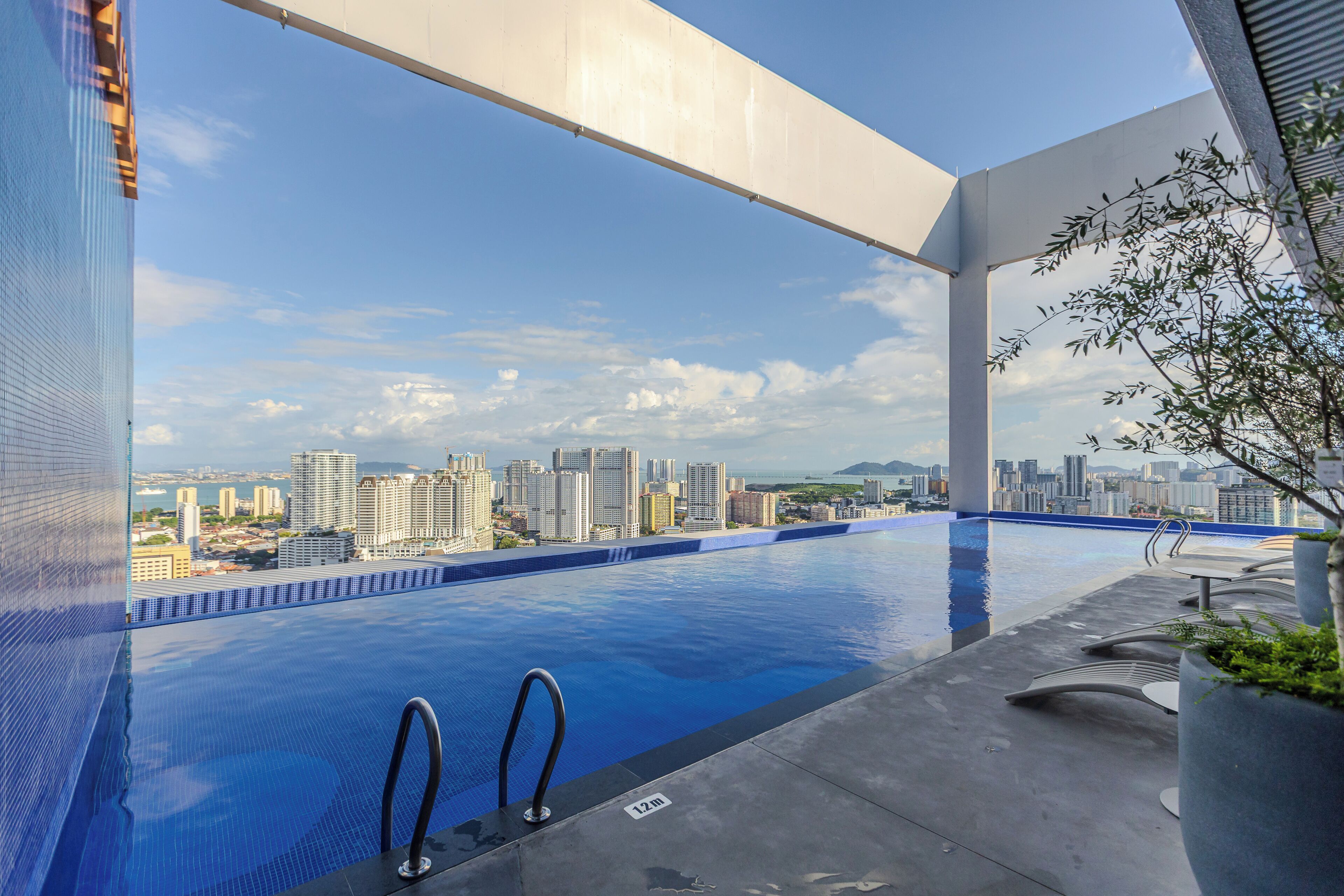 Una piscina infinita con vista al horizonte urbano, diseño arquitectónico moderno y cielo despejado.