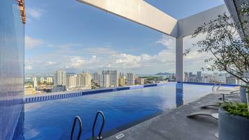 Una piscina infinita con vista al horizonte urbano, diseño arquitectónico moderno y cielo despejado.