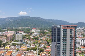 Eine Stadtansicht mit einem markanten modernen Gebäude, umgeben von Wohngebieten und einem Bergpanorama.