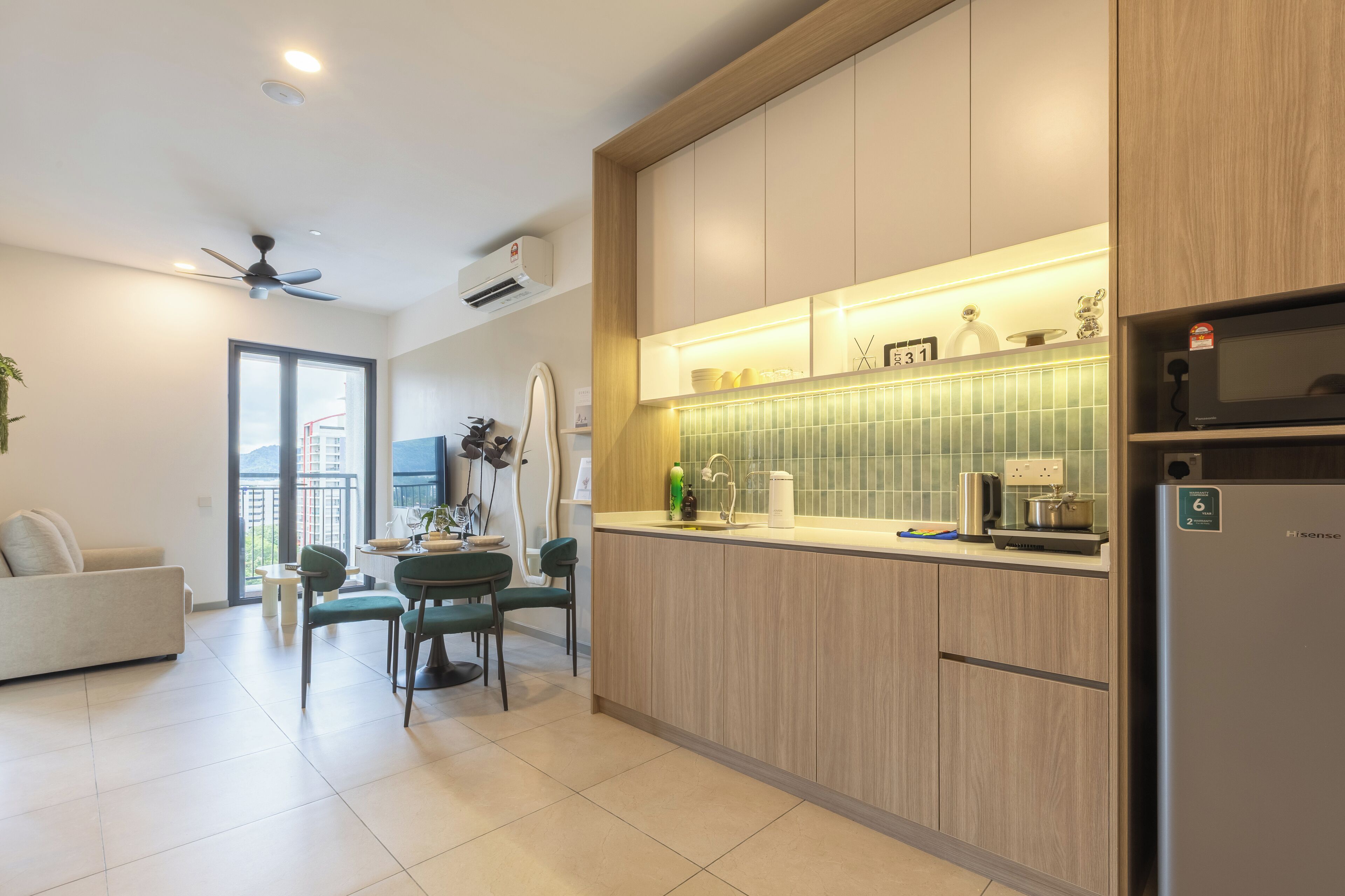 A modern kitchen with wooden cabinets, a built-in microwave, and a dining area with a green chair and a small table.