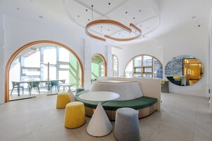 Un interior moderno con un sofá verde, otomanas amarillas y una mesa blanca.