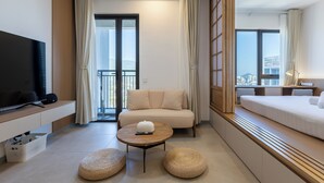 A modern hotel room with a sofa, a bed, a TV, a coffee table, and a view of the city. - 22 Macalisterz (George Town)