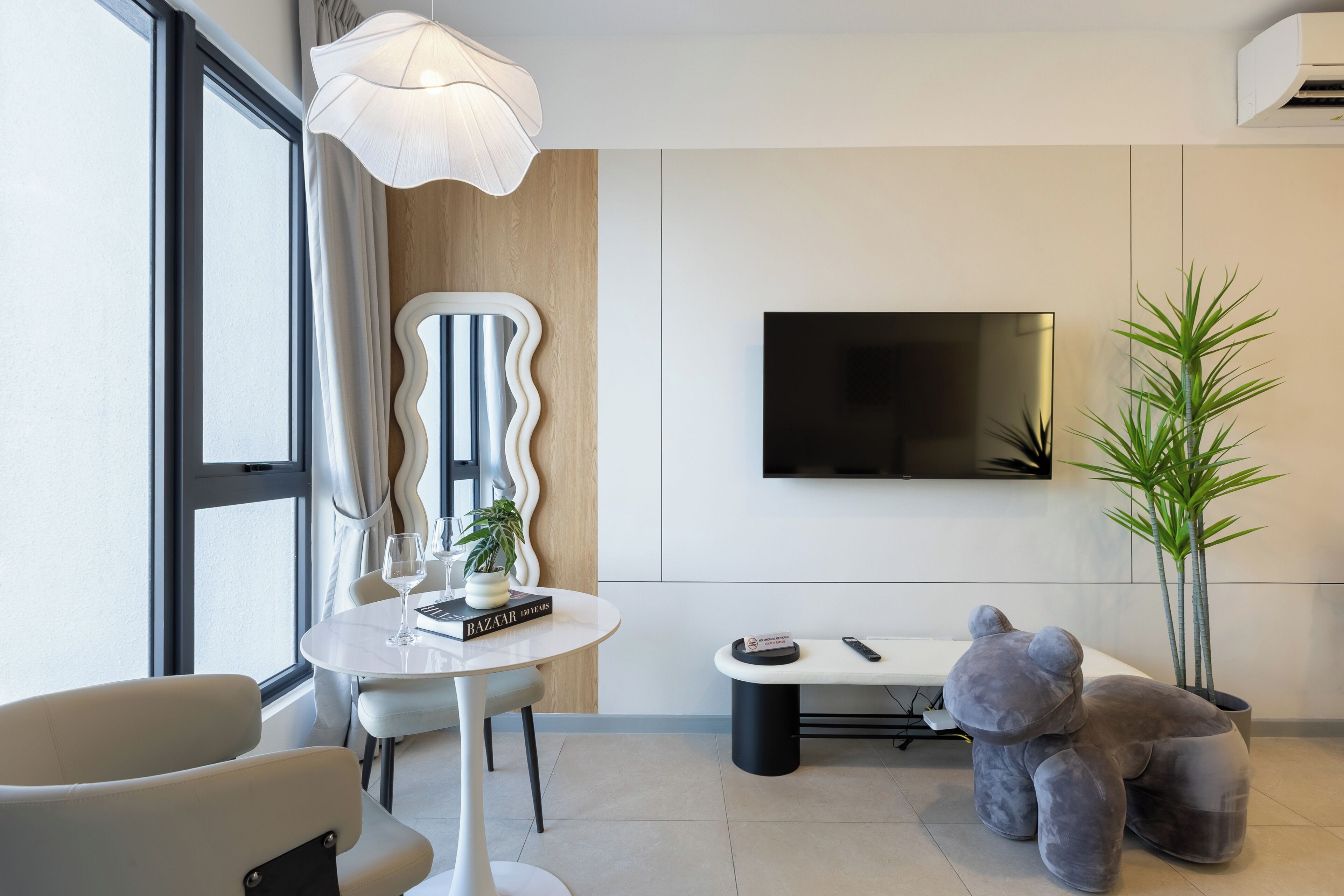 A modern living room with a round table, a sofa, a television, and a decorative plant.