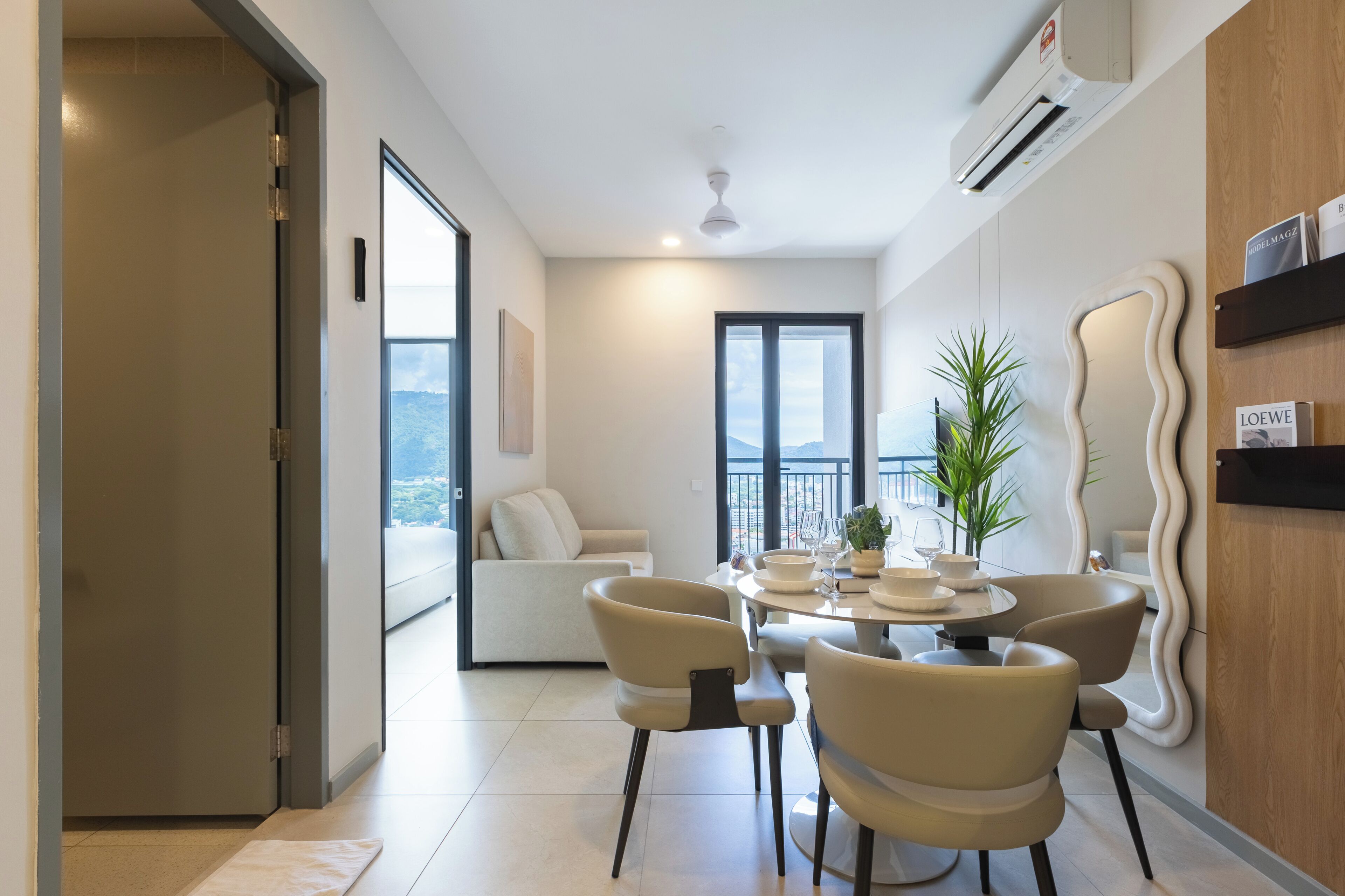 A modern dining area with a round table, four chairs, and a view of the city.