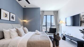 Ein modernes Hotelzimmer mit einem großen Bett, einem Deckenventilator, einem Flachbildfernseher und Blick auf die Stadt.